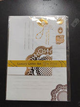 Charger l'image dans la galerie, Avant de l'emballage du set de papier à lettres Luxury Funso, illustrant des motifs de dentelle dorée et couronne sur fond blanc.